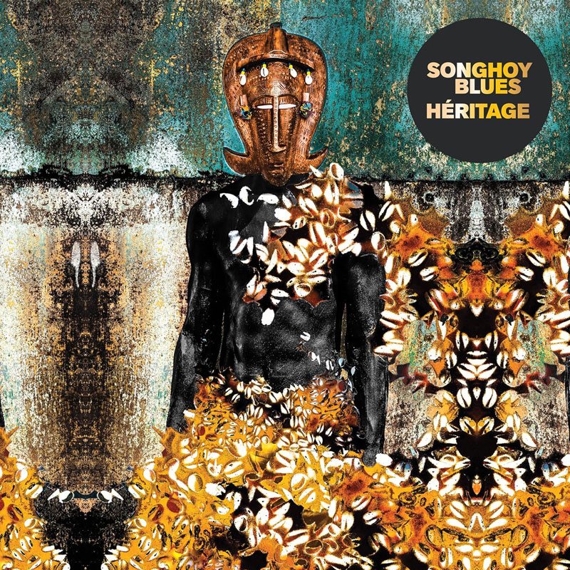 La portada del álbum Héritage de Songhoy Blues es una composición visual que fusiona elementos de la tradición y la modernidad. Presenta una figura humana de piel oscura, adornada con conchas blancas y doradas. La cabeza está cubierta con una máscara tribal tallada en madera, decorada con pequeños detalles coloridos. El fondo es una composicion o collage texturizado de tonos oxidados, verdes y dorados. En la esquina superior derecha, el título del álbum y el nombre de la banda aparecen en letras blancas y doradas dentro de un círculo negro.